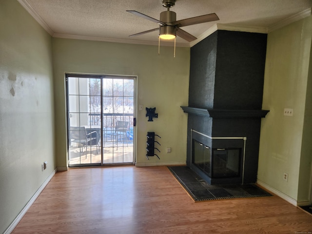 unfurnished living room with crown molding, a large fireplace, a textured ceiling, wood finished floors, and baseboards