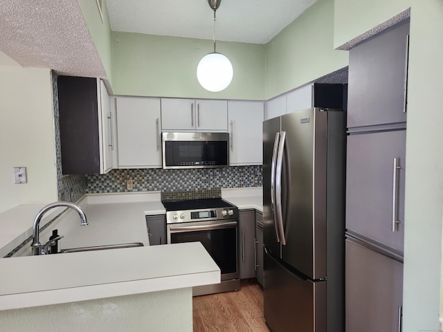 kitchen featuring white cabinets, stainless steel appliances, light countertops, and hanging light fixtures