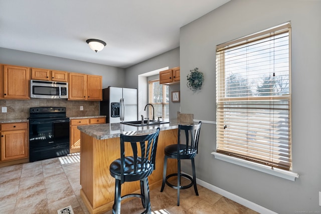 kitchen with a kitchen bar, sink, stainless steel appliances, kitchen peninsula, and tasteful backsplash