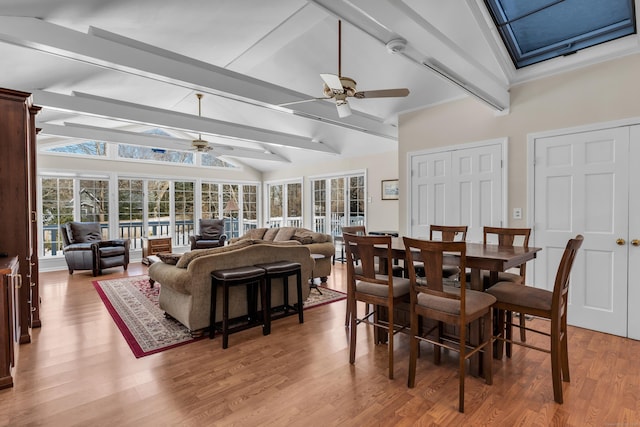 dining space featuring vaulted ceiling with beams, light wood finished floors, a wealth of natural light, and a ceiling fan