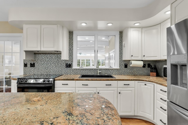 kitchen featuring stainless steel fridge with ice dispenser, white cabinetry, a sink, light stone countertops, and black / electric stove