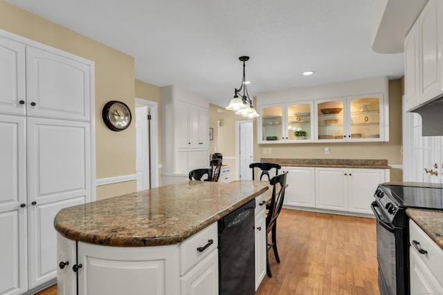 kitchen with black appliances, white cabinetry, glass insert cabinets, and a center island