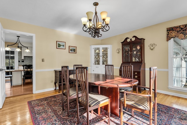 dining space with light wood-type flooring, baseboards, and a chandelier