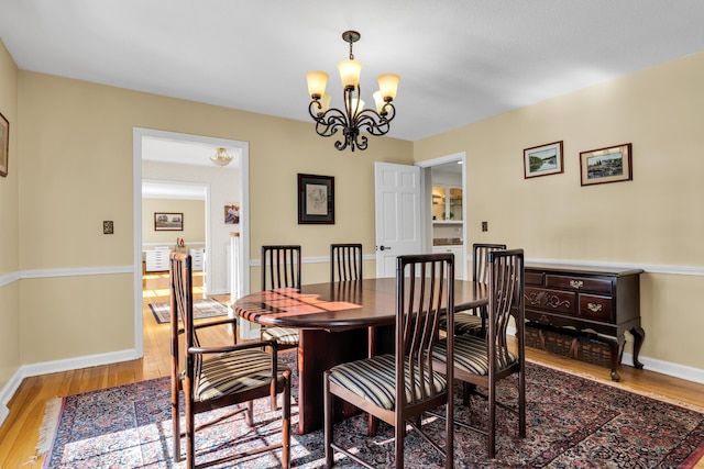 dining area featuring baseboards, wood finished floors, and an inviting chandelier