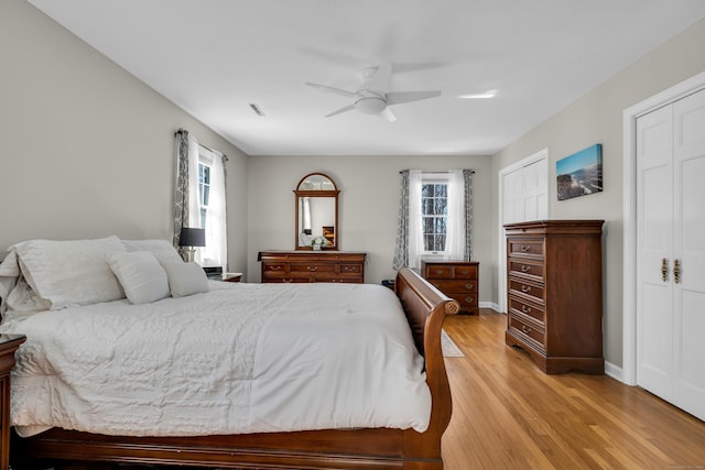 bedroom featuring a ceiling fan, baseboards, multiple windows, and light wood finished floors