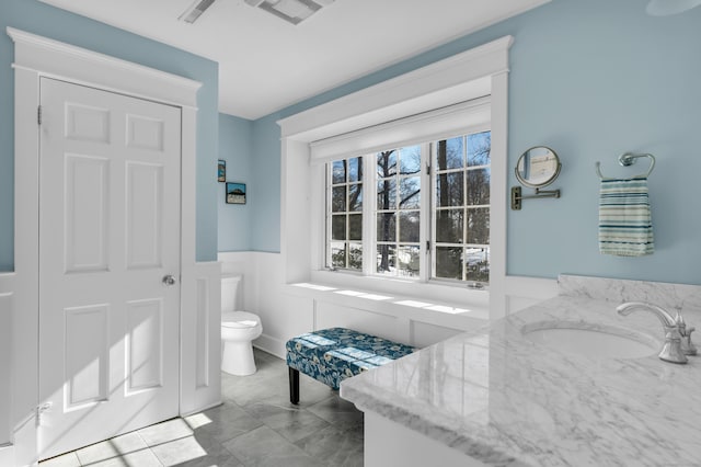 bathroom featuring toilet, wainscoting, vanity, and visible vents