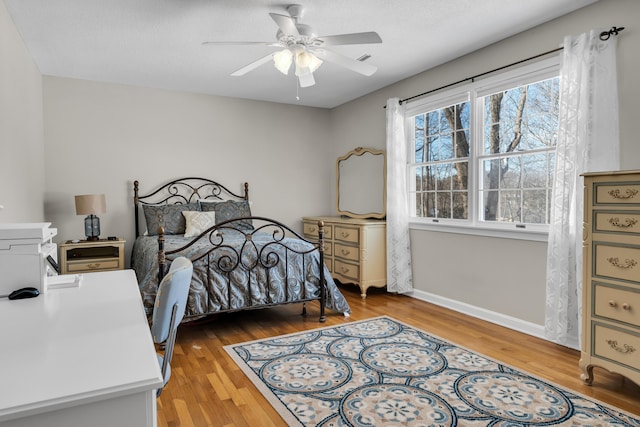 bedroom with wood finished floors, a ceiling fan, and baseboards