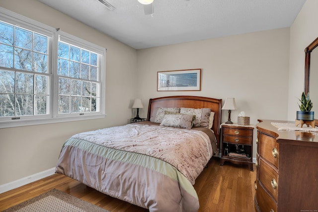 bedroom with dark wood-style floors, baseboards, visible vents, and a ceiling fan