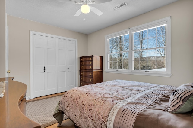 bedroom featuring a closet, visible vents, ceiling fan, and a textured ceiling