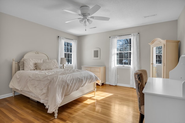 bedroom featuring multiple windows, light wood-type flooring, and baseboards