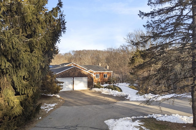 view of front of house featuring an attached garage, a chimney, and aphalt driveway