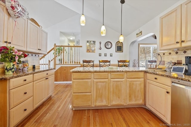 kitchen featuring arched walkways, decorative light fixtures, light wood-type flooring, light brown cabinets, and stainless steel dishwasher