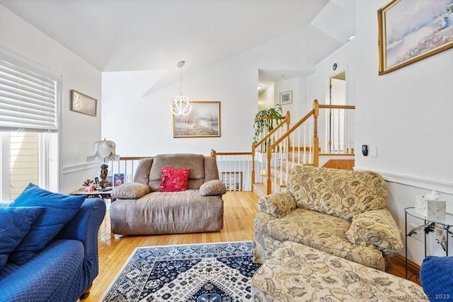 living area featuring stairs, vaulted ceiling, and wood finished floors