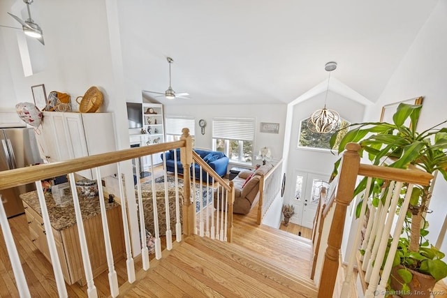 hall with vaulted ceiling, light wood-type flooring, and an upstairs landing