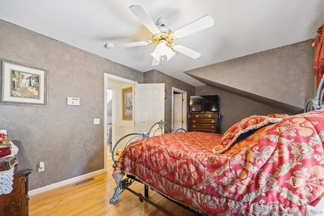 bedroom with ceiling fan, wood finished floors, visible vents, and baseboards