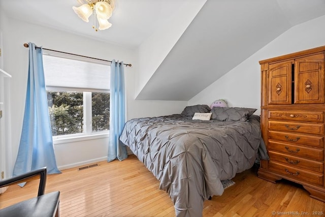 bedroom featuring light wood-type flooring, visible vents, and lofted ceiling