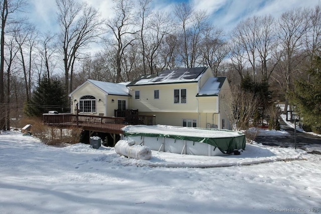 snow covered property with a covered pool and a wooden deck