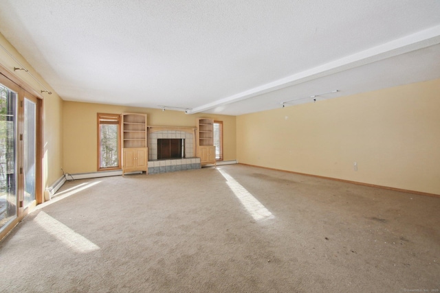 unfurnished living room featuring a textured ceiling, carpet floors, a tiled fireplace, and baseboards