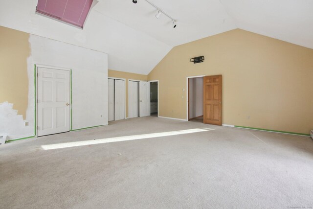 unfurnished room featuring carpet floors, rail lighting, baseboards, and high vaulted ceiling