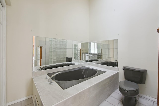 bathroom with a garden tub, tile patterned flooring, and toilet