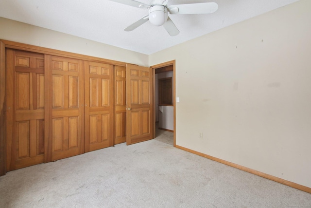 unfurnished bedroom featuring light carpet, ceiling fan, a closet, and baseboards