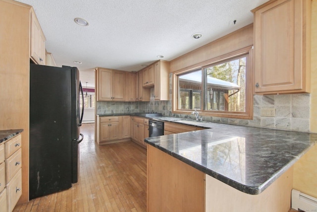 kitchen with a baseboard radiator, a peninsula, a healthy amount of sunlight, black appliances, and a sink