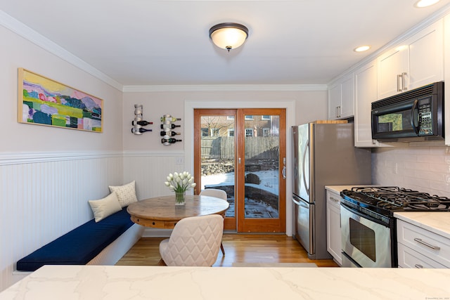 kitchen featuring breakfast area, light stone countertops, white cabinetry, and stainless steel appliances