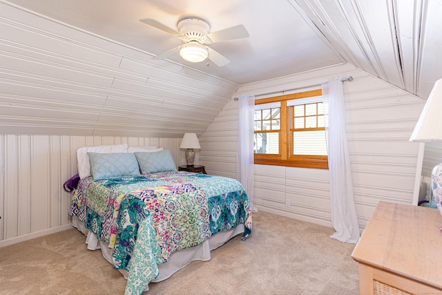 bedroom featuring lofted ceiling, wooden walls, light colored carpet, and ceiling fan