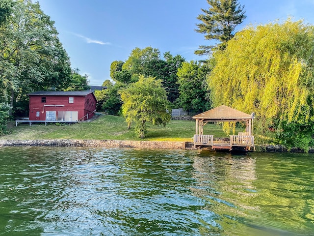 view of dock with a water view, a yard, and a gazebo