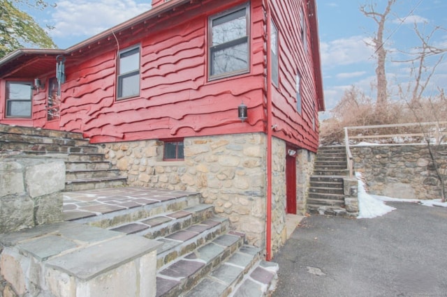 view of side of home featuring stone siding and stairway