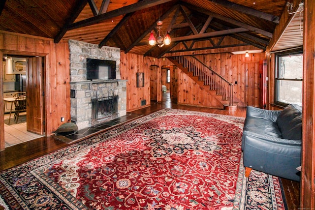 unfurnished living room with vaulted ceiling with beams, a stone fireplace, wood ceiling, and wooden walls