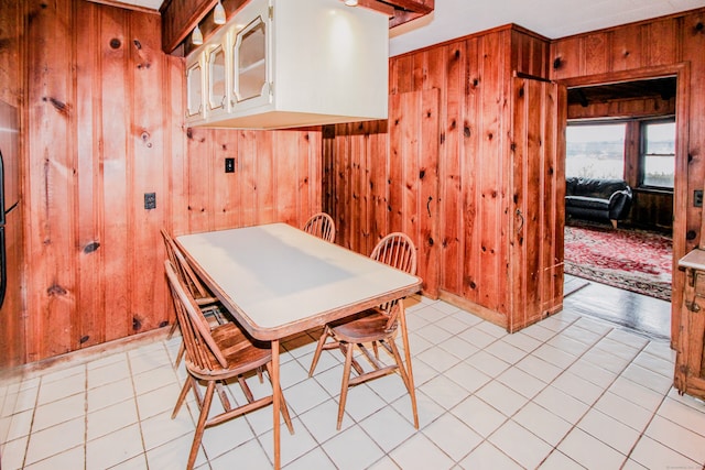 dining space featuring light tile patterned floors and wood walls