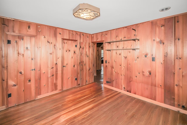 unfurnished room featuring wooden walls and wood finished floors