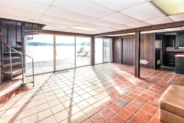 interior space with wood walls, tile patterned flooring, stairs, and a drop ceiling