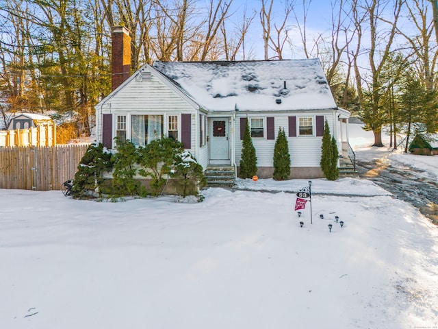 new england style home featuring a chimney and fence