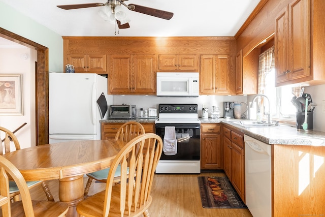 kitchen with brown cabinets, a sink, white appliances, light wood finished floors, and light countertops