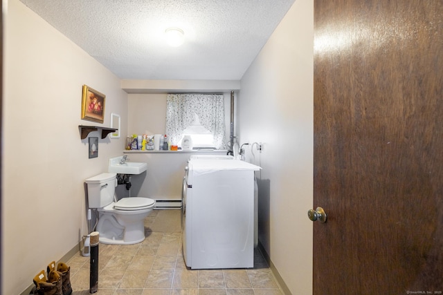 half bathroom with toilet, a baseboard heating unit, washer / clothes dryer, a textured ceiling, and baseboards