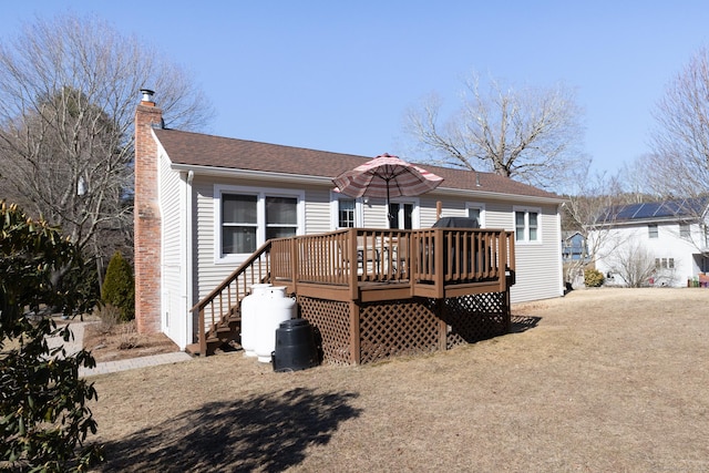 rear view of property featuring a deck, a chimney, and a shingled roof