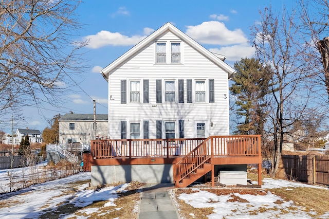 snow covered back of property with a wooden deck