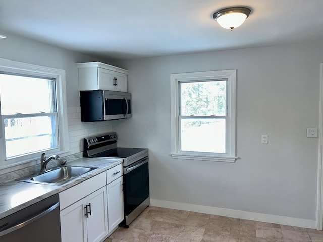 kitchen with sink, stainless steel appliances, tasteful backsplash, a wealth of natural light, and white cabinets