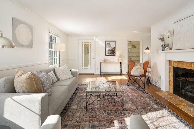 living room featuring a tile fireplace, crown molding, and dark wood-type flooring