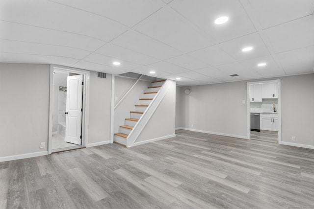 basement featuring a paneled ceiling and light hardwood / wood-style floors