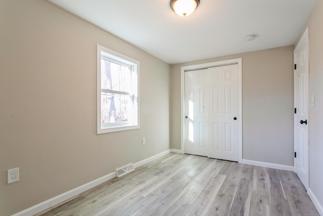 unfurnished bedroom with light hardwood / wood-style flooring and a closet