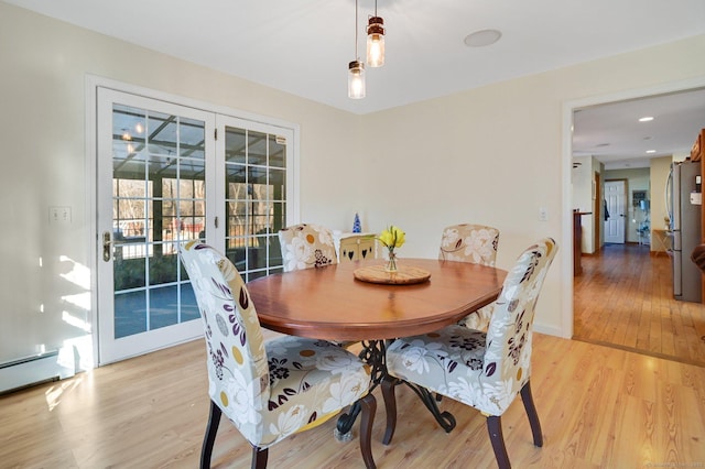 dining area featuring a baseboard heating unit and light hardwood / wood-style flooring