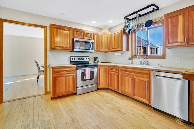 kitchen with stainless steel appliances, sink, and light wood-type flooring