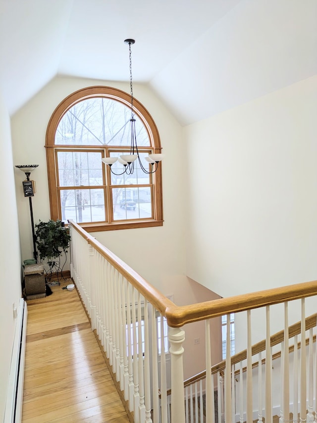 corridor featuring a baseboard radiator, lofted ceiling, a chandelier, and light wood-type flooring