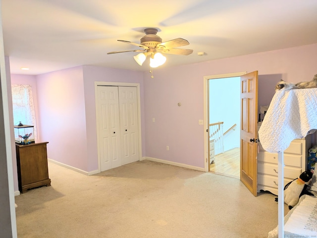 bedroom featuring light colored carpet, ceiling fan, and a closet