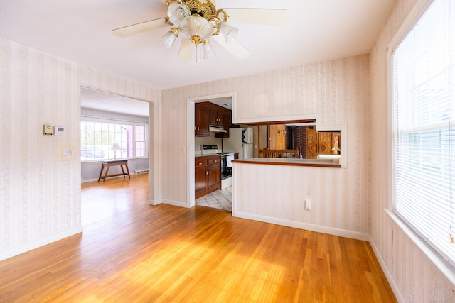 unfurnished living room with light wood-style floors, baseboards, and wallpapered walls