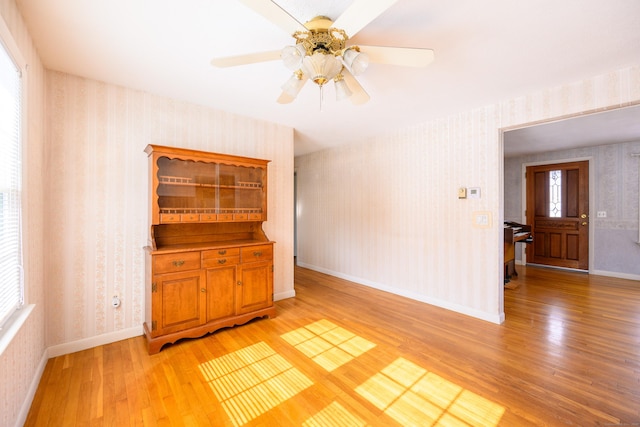 empty room with wallpapered walls, light wood-style flooring, and baseboards