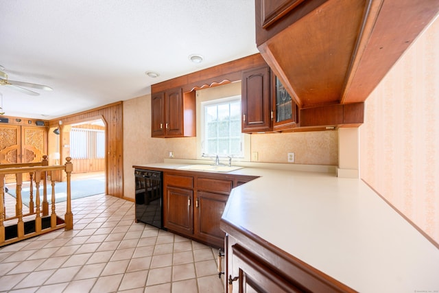 kitchen featuring light tile patterned floors, a sink, black dishwasher, light countertops, and wallpapered walls